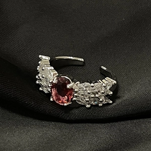Primer plano de anillo abierto de plata con gema roja ovalada y circonitas blancas