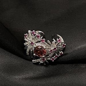 Detalle del anillo con circón rojo, montura floral y cristales color púrpura