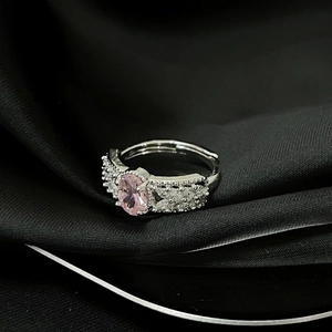 Detalle de anillo ajustable de plata con circón rosa sobre fondo de seda negra