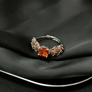 Detalle de anillo ajustable de plata con piedra naranja de corte cojín y pavé de circonitas