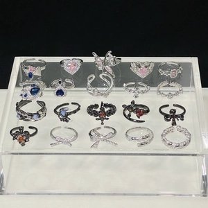 Set aus 20 verstellbaren Ringen mit rosa Schleifen und bunten Kristallen auf schwarzem Grund