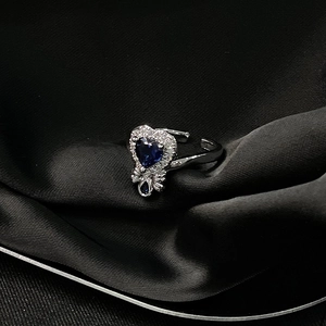 Detail eines herzförmigen blauen Edelsteinrings mit verstellbarem Silberband auf Seide