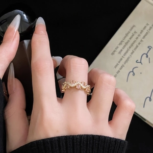 Dettaglio dell'anello dorato ondulato con gemma rosa e pavé di zirconi bianchi lucidi