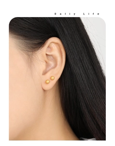 Gros plan de boucles d'oreilles boules dorées mates minimalistes sur le mannequin