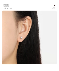 Gros plan de boucles d'oreilles boules argentées mates portées par un mannequin au quotidien