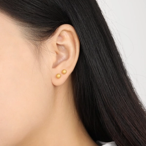 Boucles d'oreilles boules dorées mates minimalistes portées pour un style chic