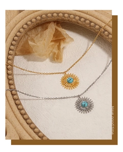Detailed view of sunburst pendant with turquoise inlay in gold and silver finish