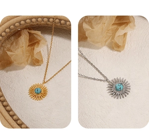Detail view of gold and silver sunburst pendants with turquoise inlay on chain