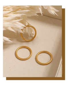 Detailopname van drie 2mm matte gouden titanium stalen ringen op een beige dienblad