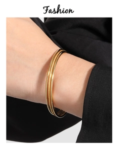 Detailed view of three-piece stackable gold titanium bracelets with matte and polished finish