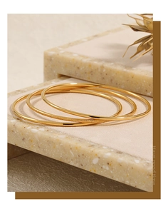Detailed close-up of a three-piece gold titanium steel bangle set with frosted and smooth finishes