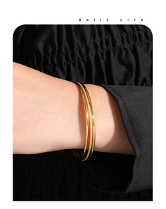 Detail of three-piece stackable gold titanium bracelets with matte and polished finishes