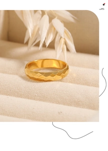 Detail eines goldenen Titan-Rhombusrings mit Textur in einer cremefarbenen Schmuckdose