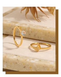 Primer plano de anillo de mariposa dorado y anillo de diamantes en soporte de piedra