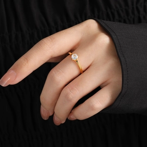 Elegante anillo de acero de titanio dorado con un diamante solitario para mujer chic