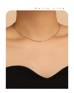 Detailopname van een minimalistische fonkelende fijne ketting van verguld titaniumstaal om de nek