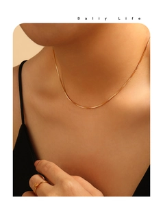 Detalle del collar de cadena de caja dorada de 1mm y anillo de flor en modelo