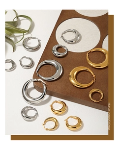 Detail view of thick gold and silver hoop earrings in various sizes on a textured background