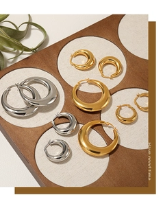 Detail view of gold and silver thick hollow hoop earrings in various sizes on a dark board