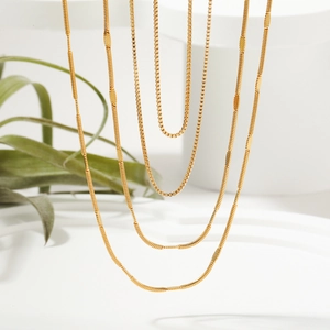 Tres elegantes collares de oro de 18K con cadena de caja y serpiente sobre fondo blanco