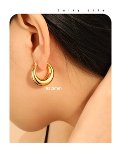 Detail of 2.5mm chunky golden hoop earrings with polished finish on model ear