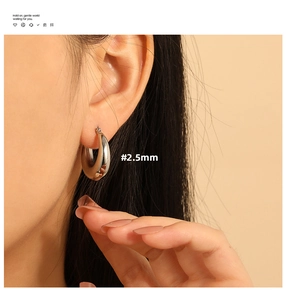 Close-up of 2.5mm thick silver hoop earrings worn by a model for a minimalist aesthetic