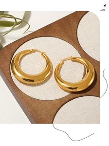 Detailed view of thick golden hoop earrings with mirror polished finish on fabric