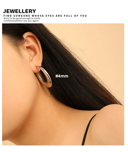 Detail view of large 4mm thick polished silver hoop earrings on female model