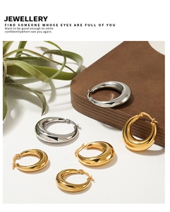 Polished gold and silver teardrop hoop earrings on a natural wood and white background