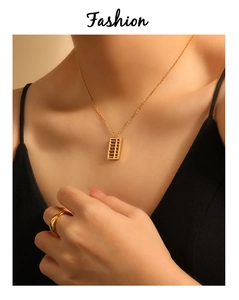 Macro detail of gold abacus pendant necklace and quilted pattern ring on model