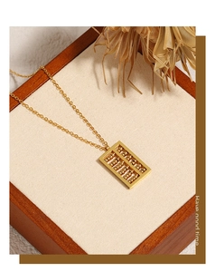 Macro detail of a golden abacus pendant necklace on a velvet jewelry display box