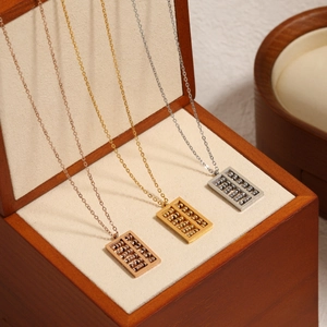 Three Chinese abacus necklaces in rose gold, gold, and silver finishes on a wood display