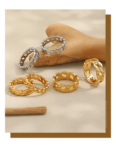 Detailed view of gold and silver Cuban link rings displayed on sand and wood