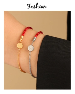 Detail of red braided rope bracelet with gold and silver Fu character pendant