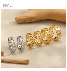 Macro shot of gold and silver Cuban link chain rings on natural wood and sand background
