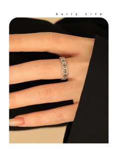 Macro shot of silver Chinese coin pattern open ring worn on finger with elegant suit styling