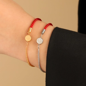 Traditional red braided rope bracelet with gold metal chain and round Fu pendant detail