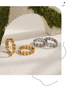 Detail of gold and silver Chinese coin rings displayed on a white stand with green moss