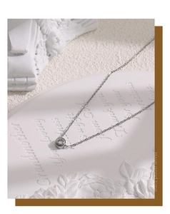 Macro shot of a silver zircon solitaire necklace on an elegant white textured background