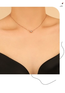 Detailed view of rose gold zircon necklace on model featuring a minimalist solitaire pendant