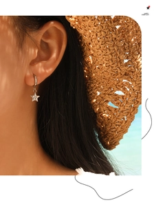 Detail of silver star hoop earring with clear zircon inlay on a female model