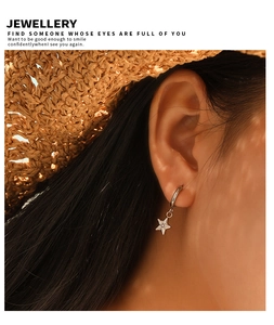 Close-up of star-shaped earrings with zircon inlay worn by a model in soft summer sunlight