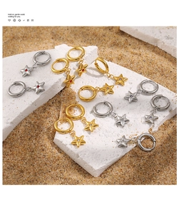 Detailed macro of gold and silver star hoop earrings with zircon stones on natural background