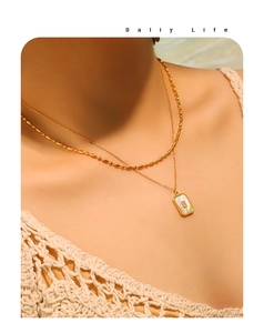Detail of layered gold double necklace with rectangular mother of pearl pendant on model
