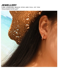 Gros plan d'une boucle d'oreille minimaliste en acier doré avec cristaux sur un mannequin