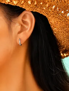 Détail d'une boucle d'oreille en acier argenté avec zircons portée par un modèle