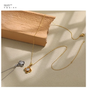 Detailed view of gold and silver clover necklaces with zircons on textured stone