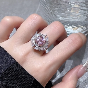 Makroaufnahme von rosa Edelsteinring mit Zirkonia-Halo auf dem Finger getragen
