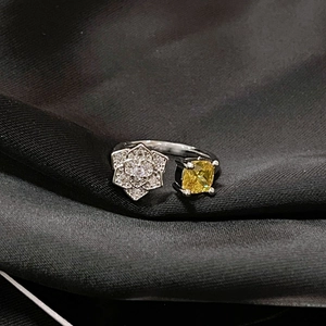 Primer plano de un anillo bypass de plata con flor de pavé y gema amarilla cuadrada