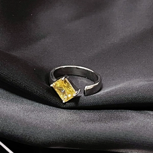 Foto macro de un anillo de circonita amarilla rectangular con banda ajustable